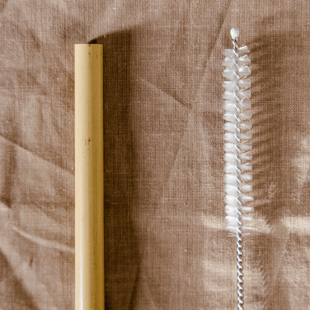 Cepillo para pitillo a lado un pitillo de bambu con fondo de tela
