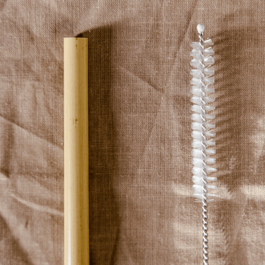 Cepillo para pitillo a lado un pitillo de bambu con fondo de tela