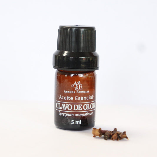 Aceite esencial de clavo de olor de Ananda a lado unos clavos de olor fondo blanco.