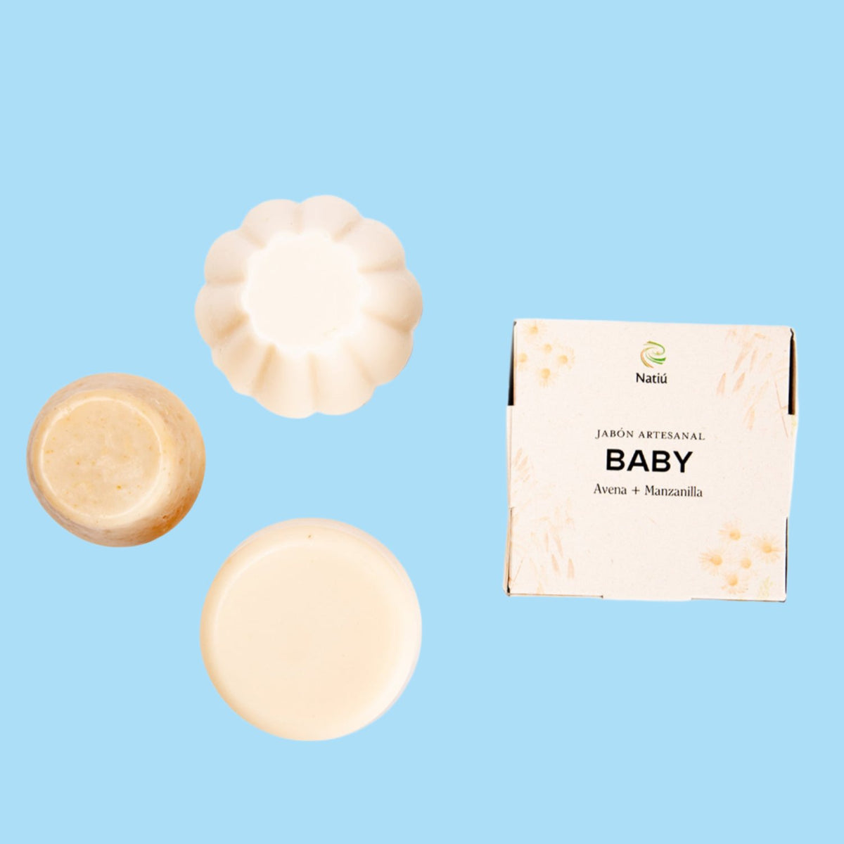 Jabón Facial para bebe a lado su caja con fondo azul claro