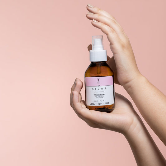 el tónico facial agua de rosas de aruná en manos de una mujer.
