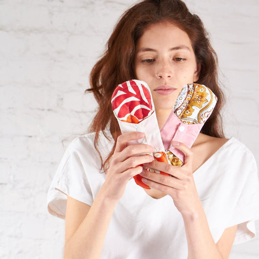 una mujer con dos Toallas Higiénicas Reusable en Tela en su manos.