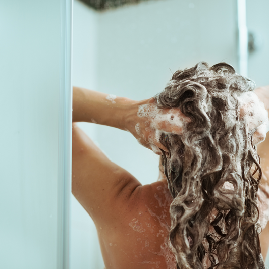 una chica usando el shampoo natural de romero y uchuva de selva morada.