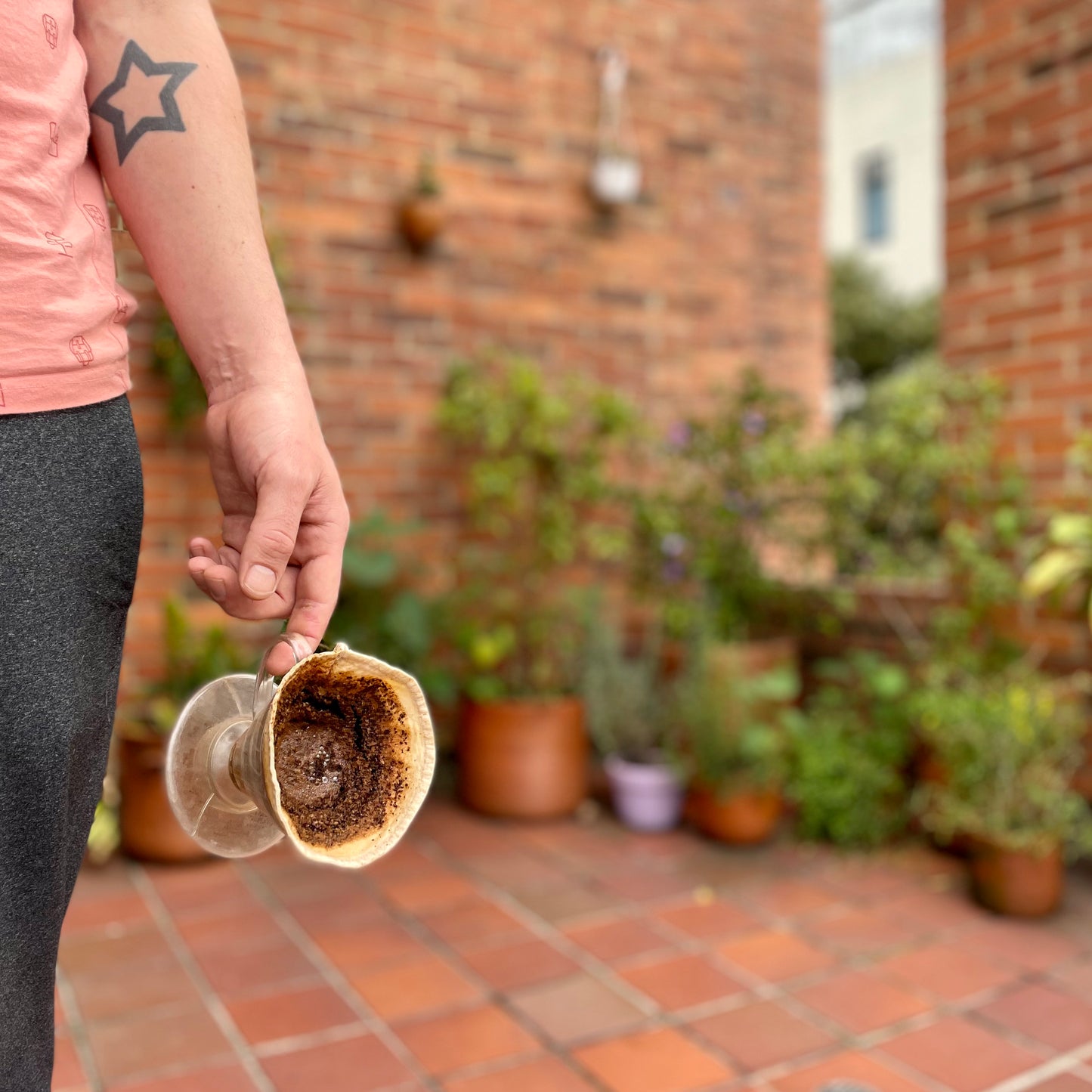 Filtro para café en tela reutilizable para dripper v60 lleno de cafe en el mano de un hombre.