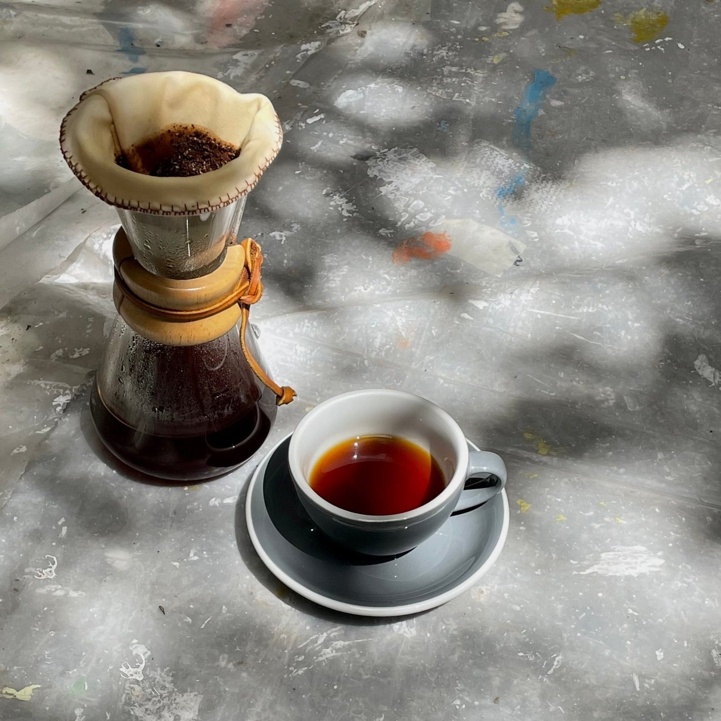 Filtro para café en tela reutilizable en un chemex a lado un vaso de cafe ya listo para tomar. 