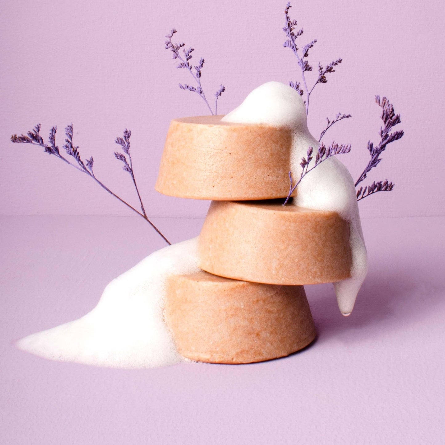 tres shampoos de lavanda con una planta de lavanda y espuma. 