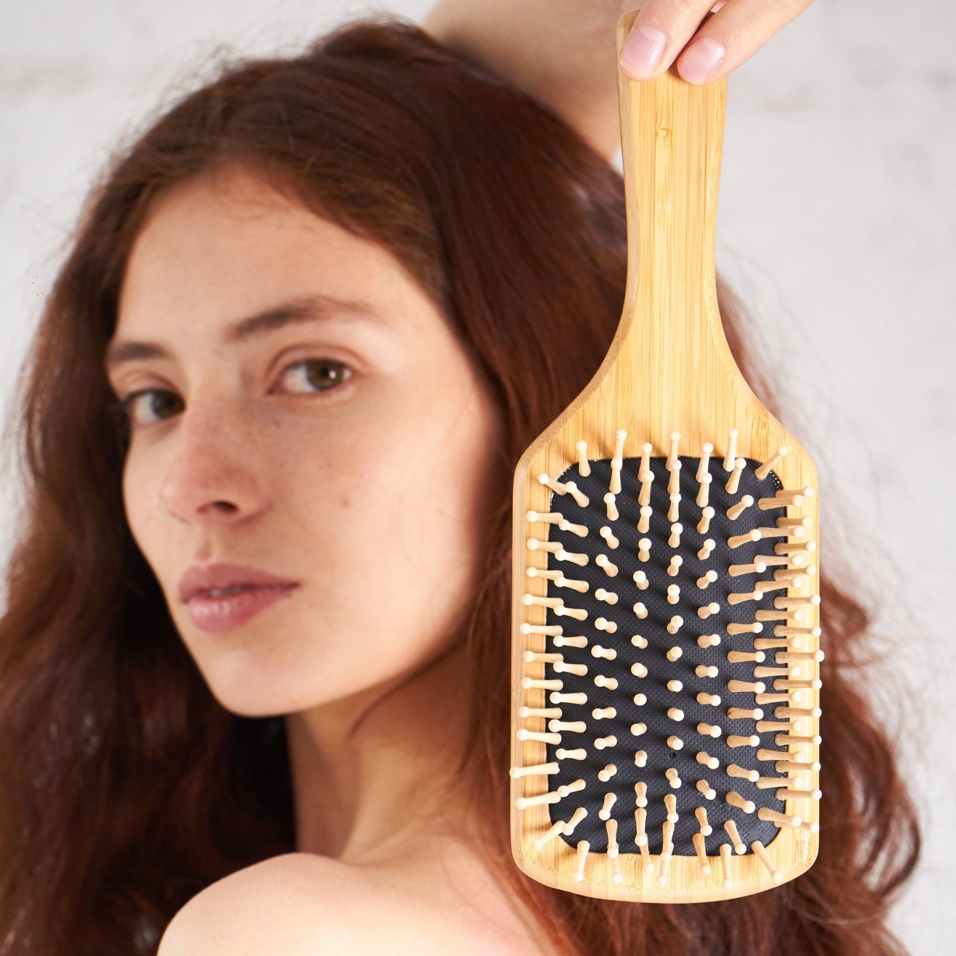 Cepillo para Cabello Anti Frizz en el mano de una mujer con cabello largo. 