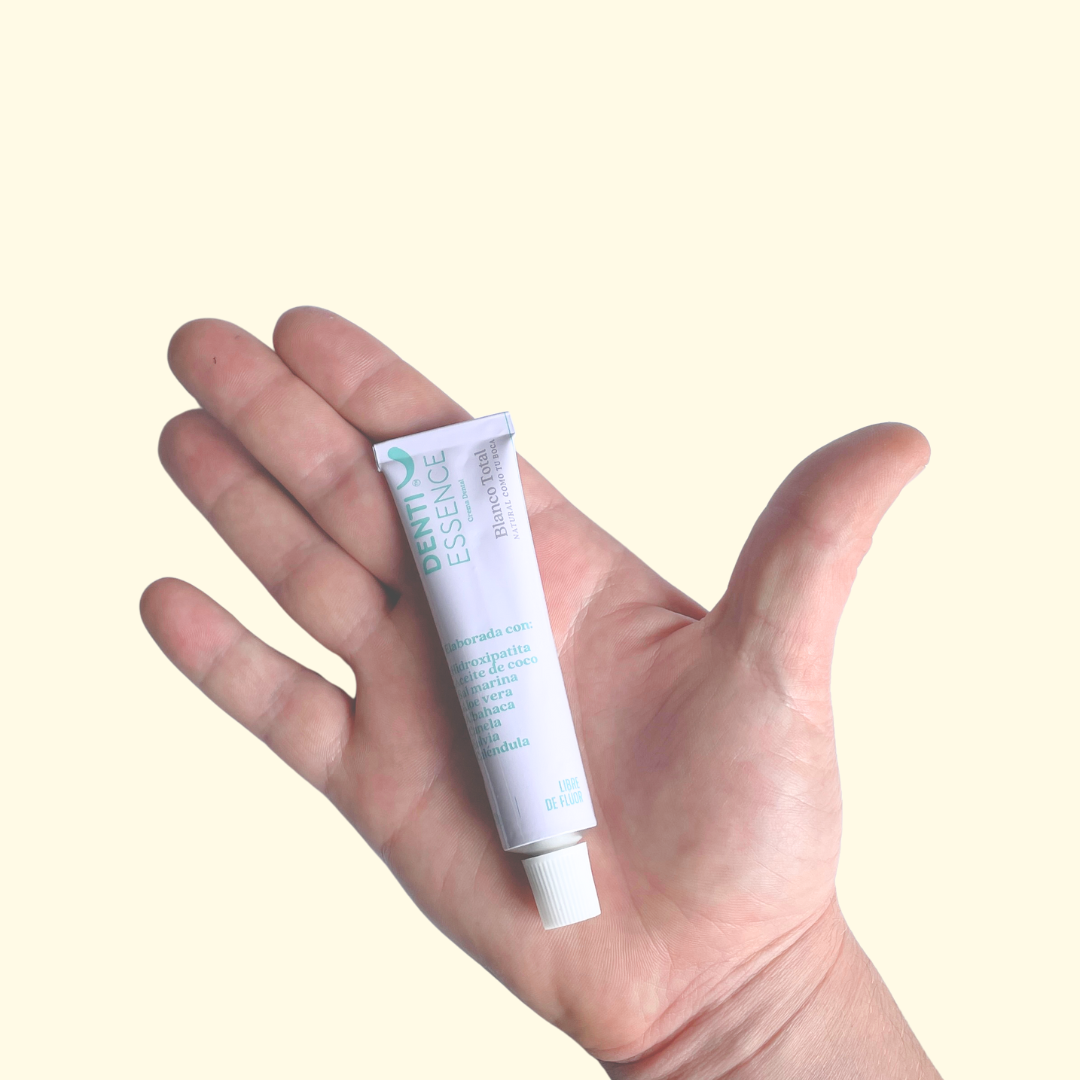 la crema dental sin fluor de denti essence 20g en un mano de un chico. 