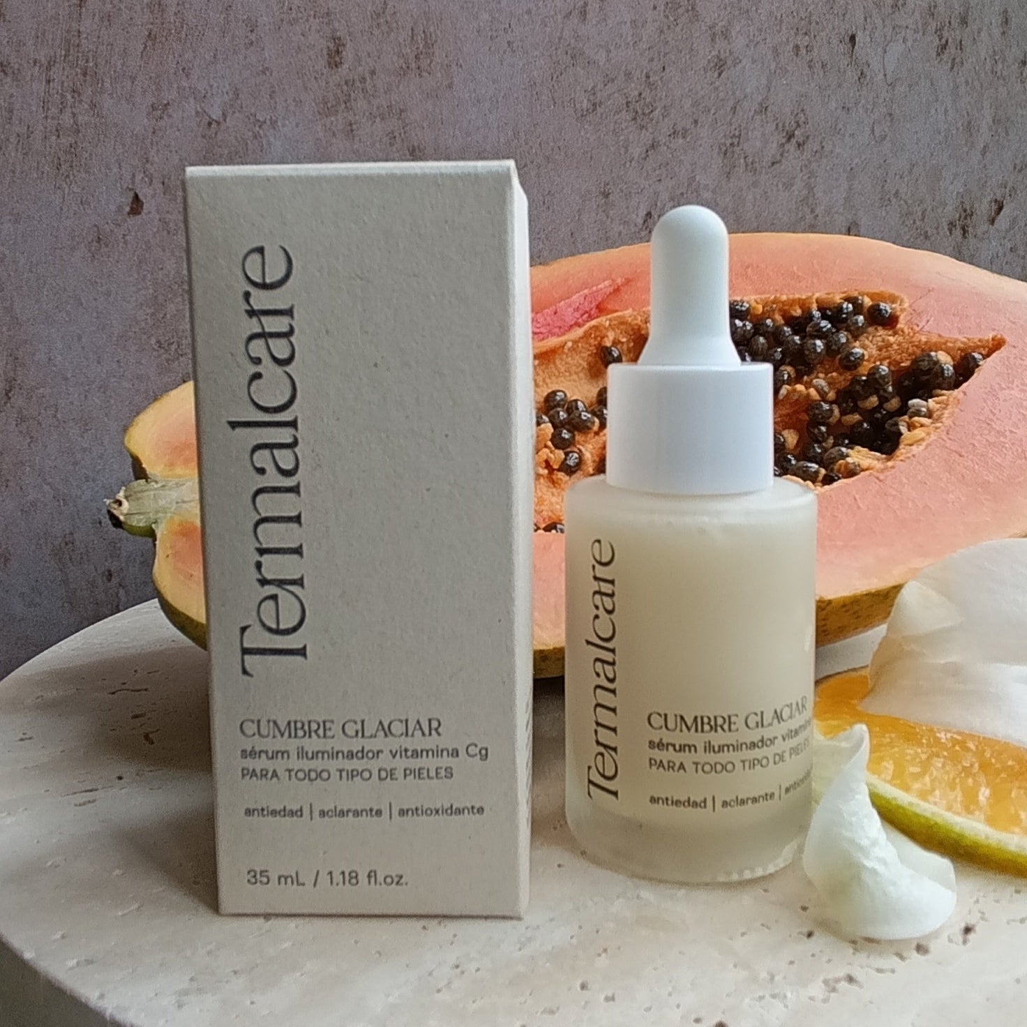 la caja y botella de serum vitamina c de termalcare con frutas a lado. 